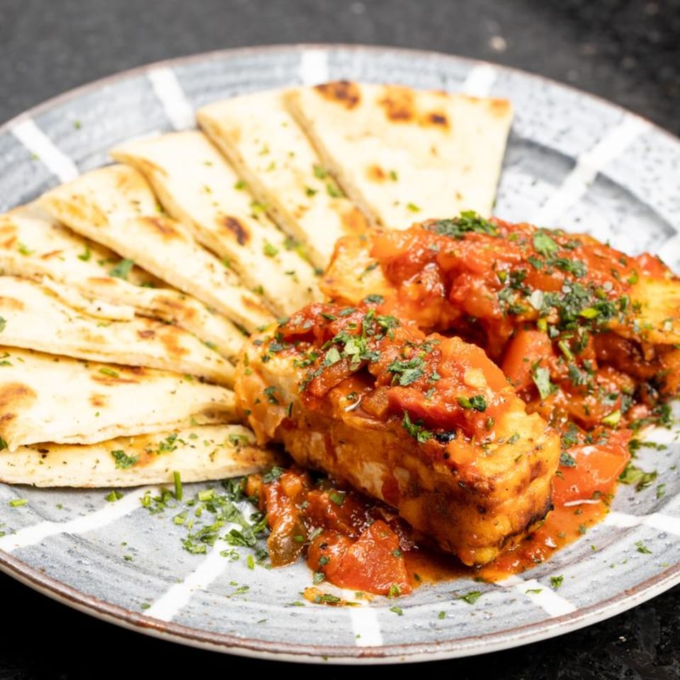 Greek City Restaurant's grilled halloumi cheese with tomato sauce and pita bread on a plate.