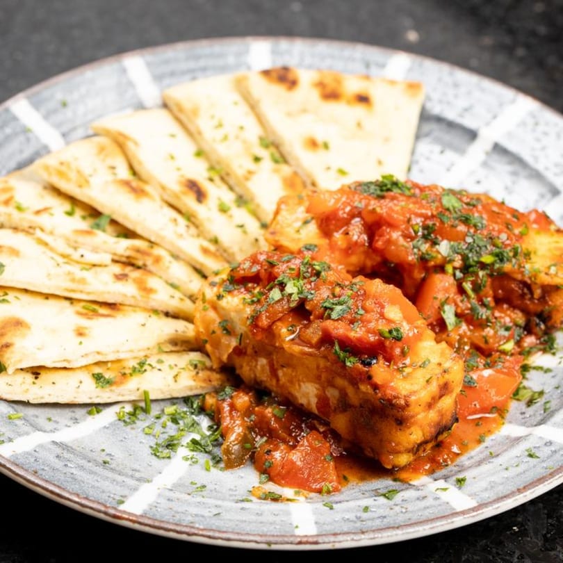 Greek City Restaurant's grilled halloumi cheese with tomato sauce and pita bread on a plate.